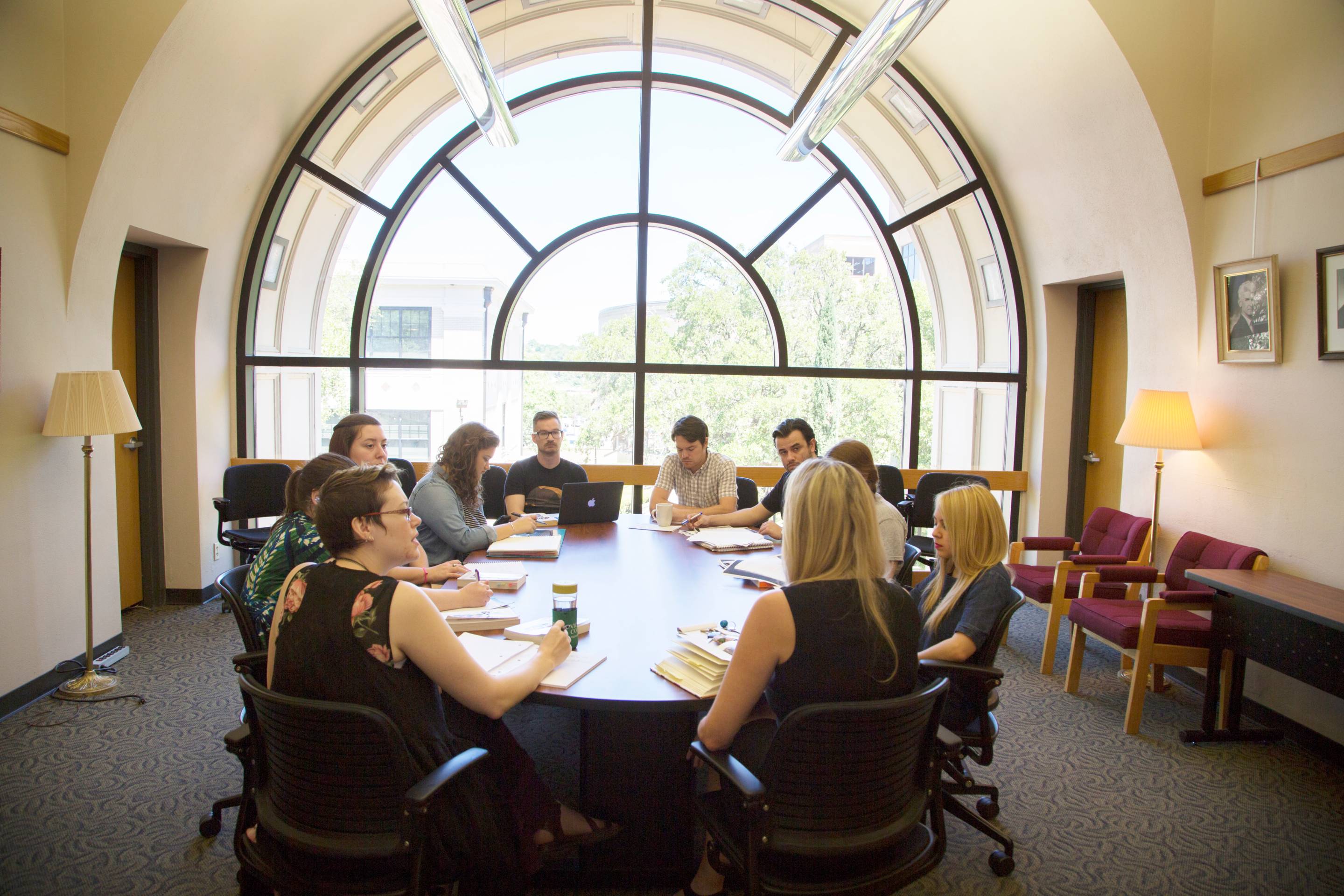 group of people meeting around a table in a well lit conference room