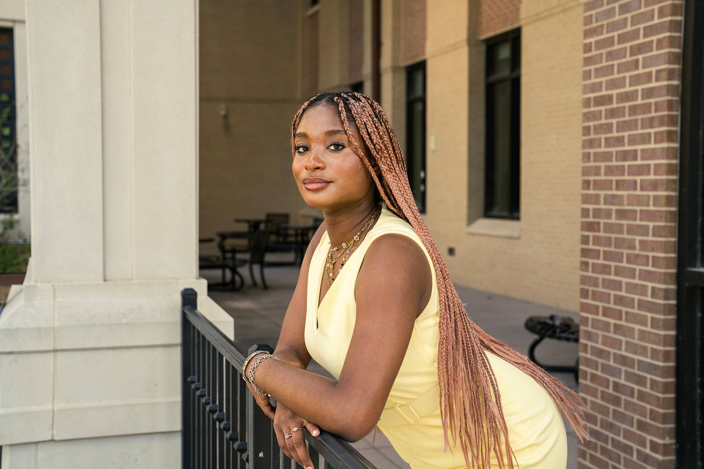 woman in yellow dress leans forward on metal railing
