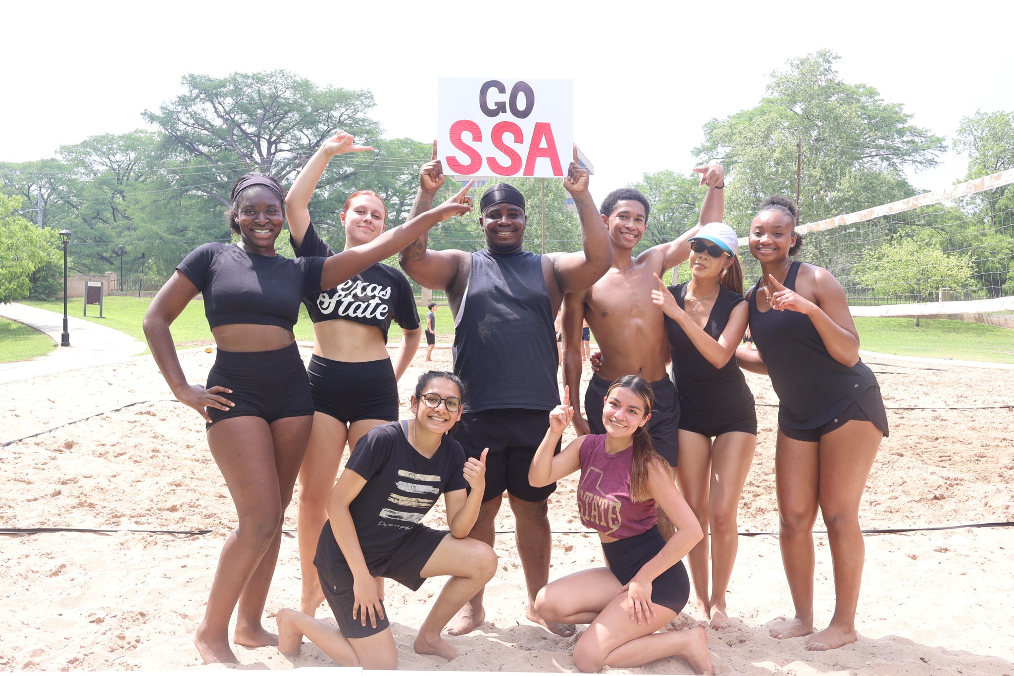 Students on a sand volleyball court with a "Go SSA" sign
