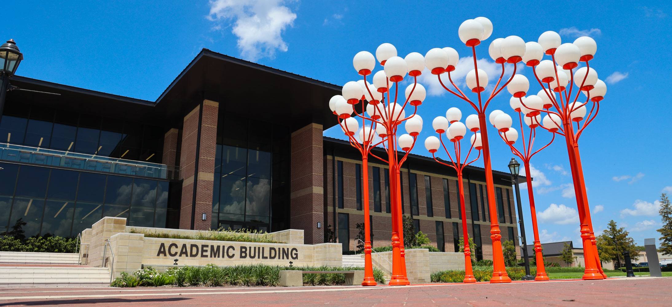 exterior of red brick building with orange light posts
