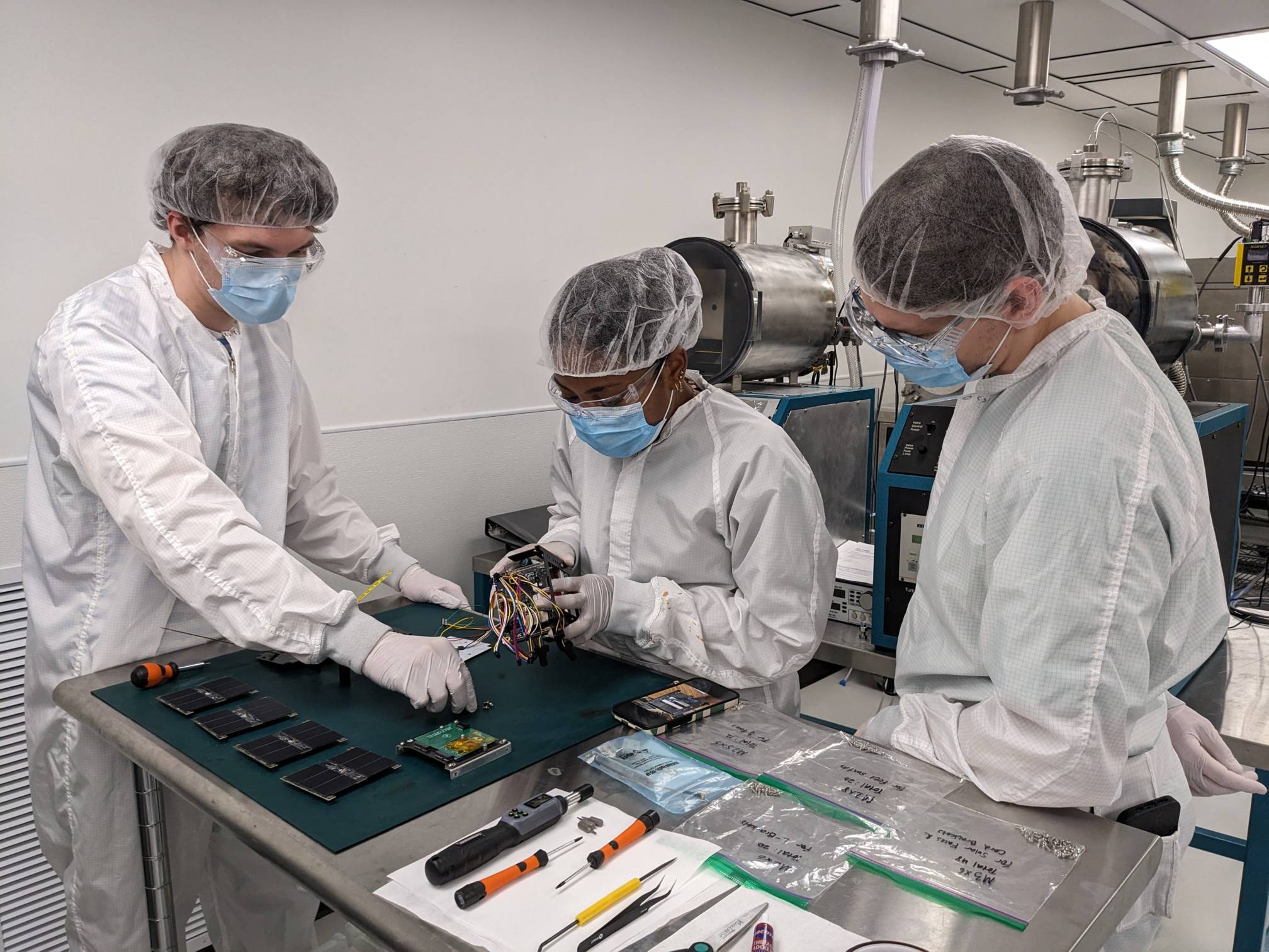 three people posing with small black box