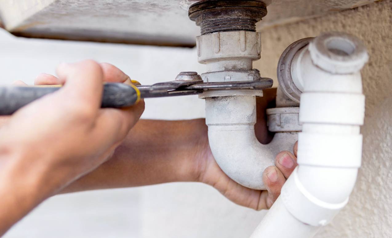someone tightening a sink pipe with a wrench