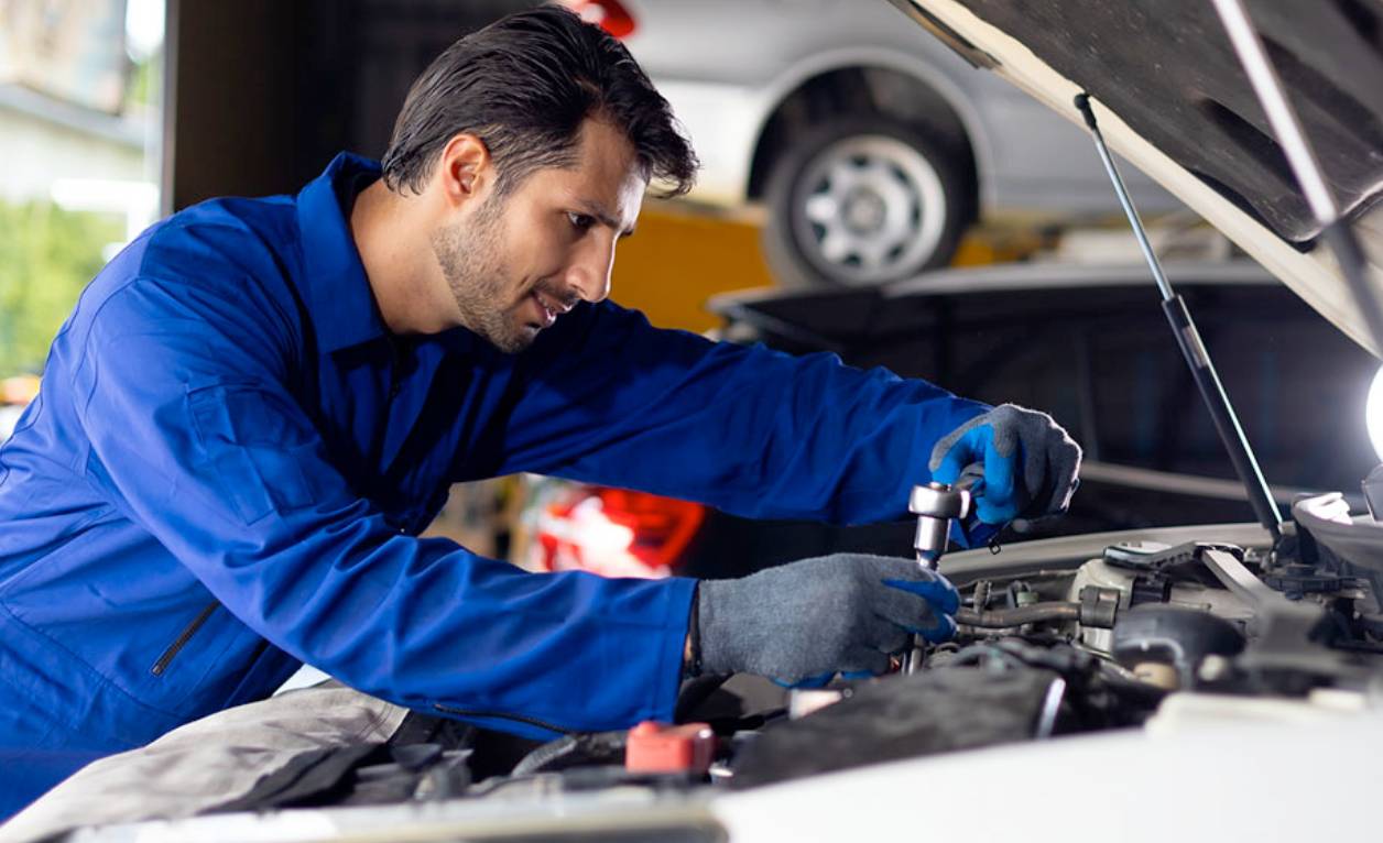 an auto tech working under the hood of a car
