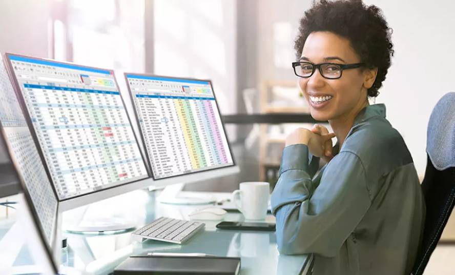 a woman facing the camera and smiling in front of computer monitors