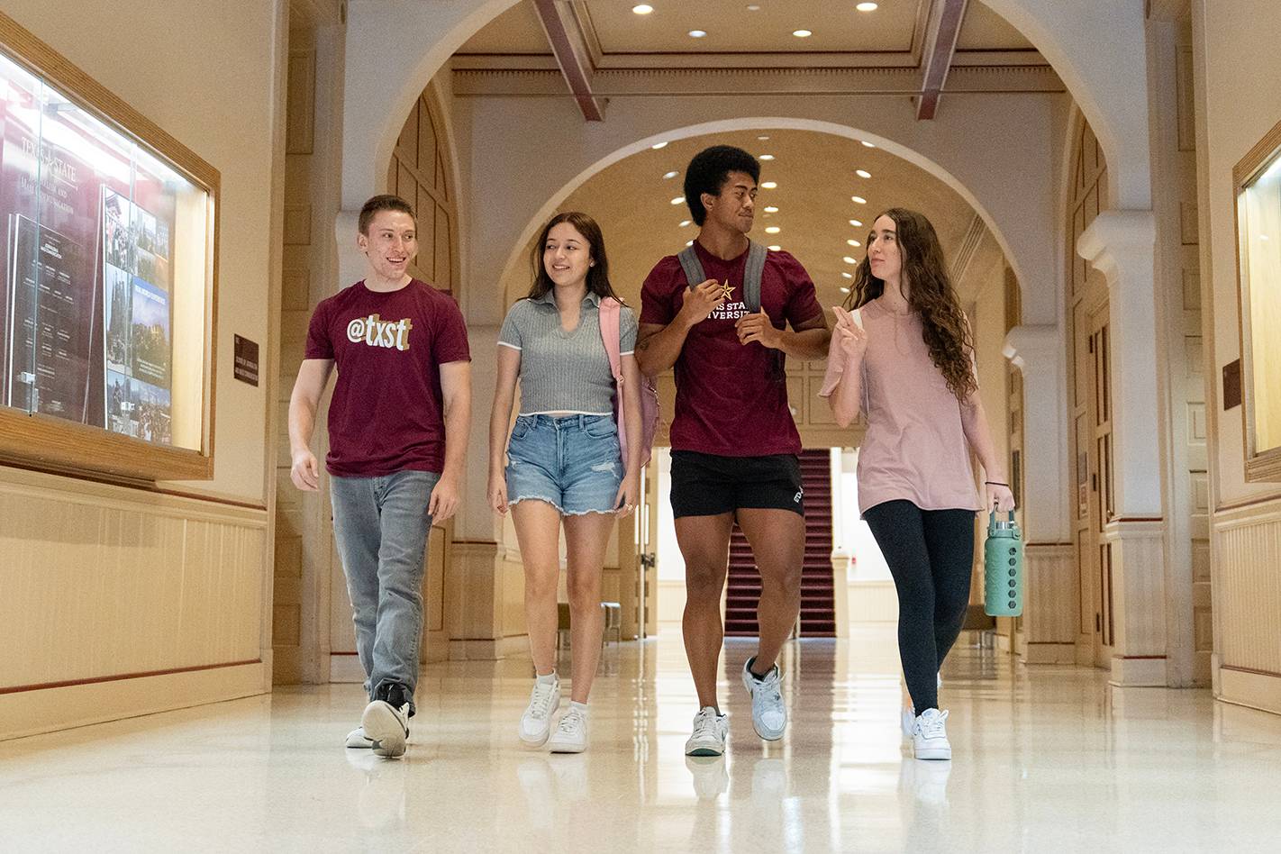 four students walking down hallway