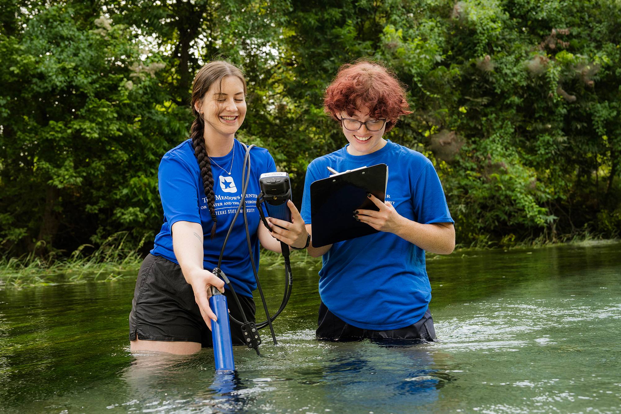 two women standing in waist-deep water conducting research