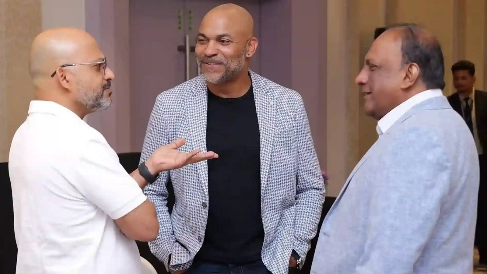 three professionally dressed men chat at conference