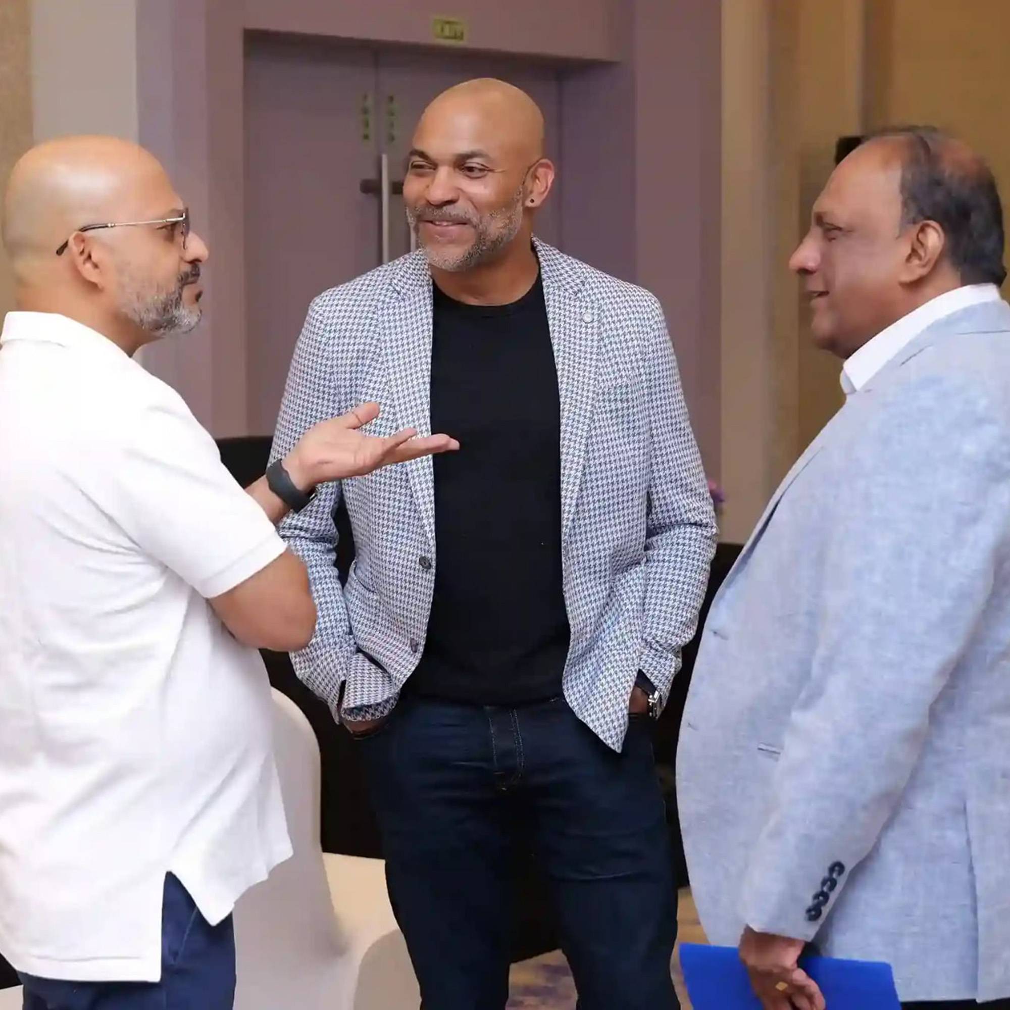 three professionally dressed men chat at conference
