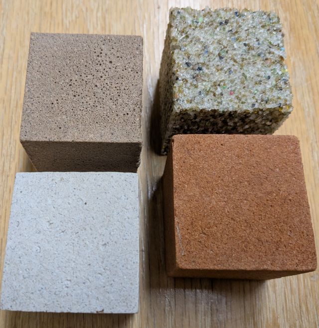 four cudes of different composite materials sitting on wooden table