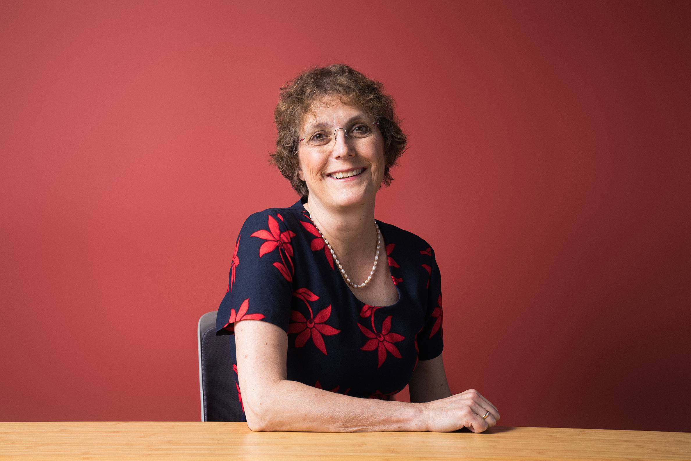 Andrea Golato sitting in front of red wall at wooden table