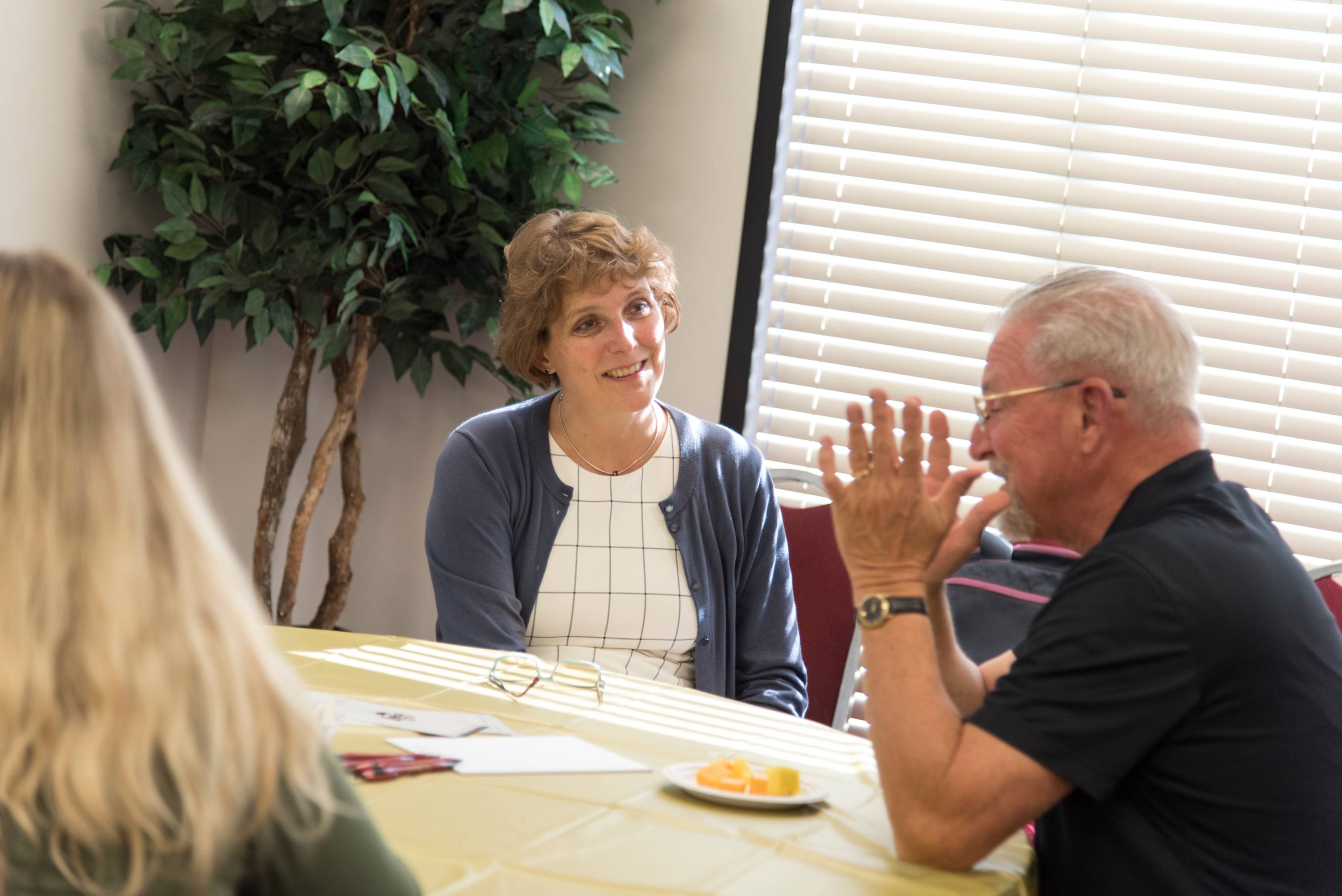 woman listens to man speak and they sit at a table