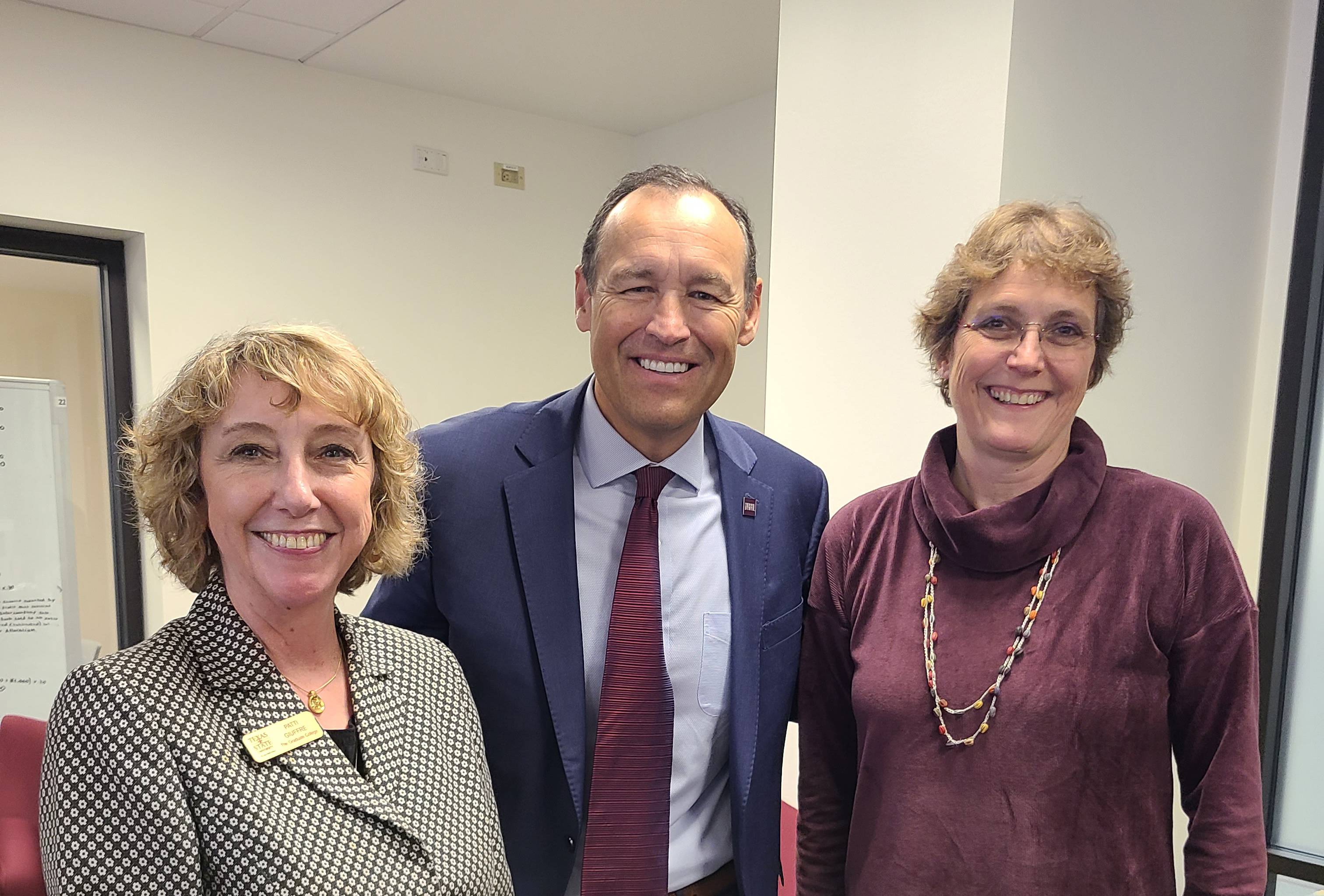 man and two women in business attire pose for photo