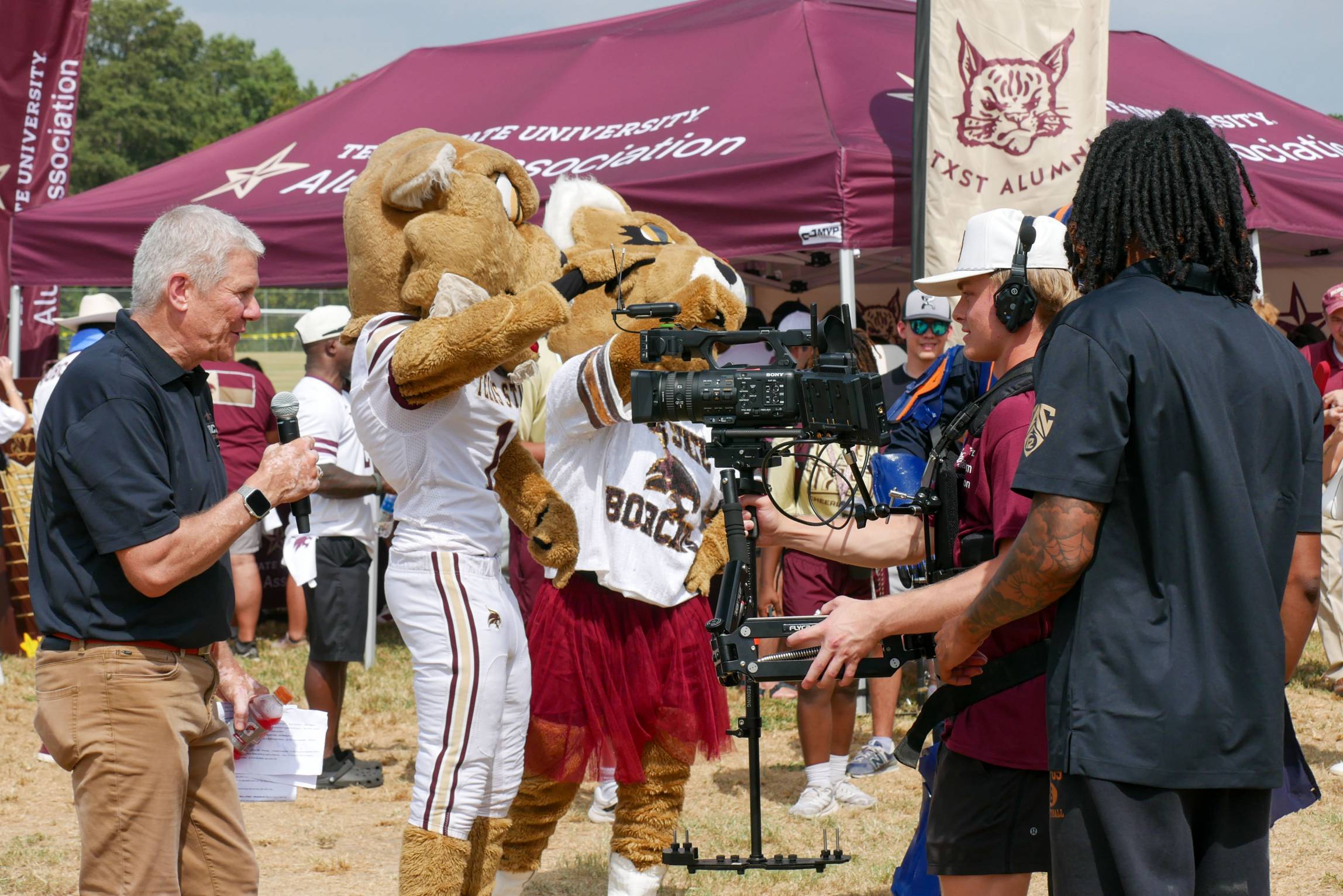 A camera crew films a Bobcat Game Day segment featuring Texas State mascots at a pregame event.