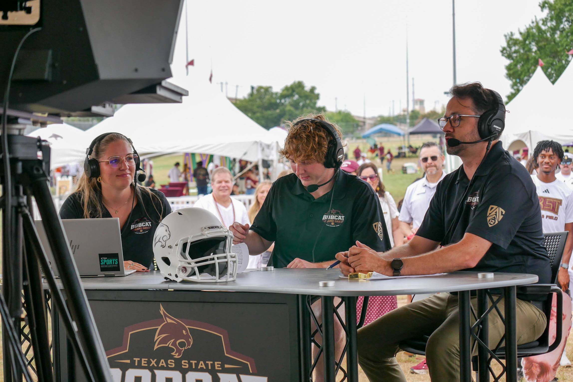 Bobcat Game Day hosts wearing headsets sit at the broadcast desk during the live pregame show.