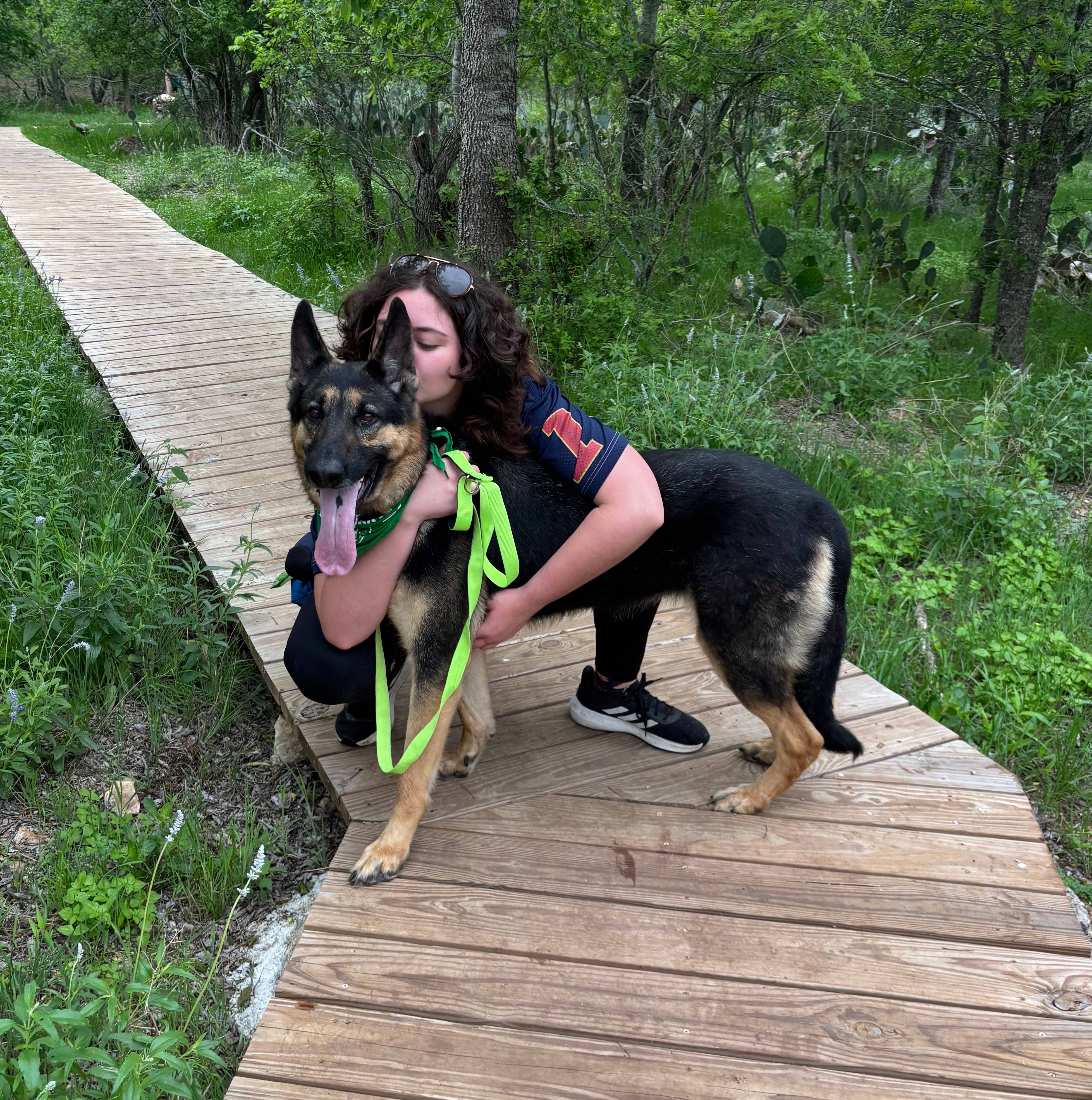 woman hugging a german shepard on wooden walk way