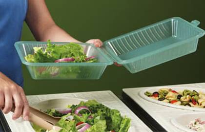 Someone holding a plastic clamshell container and placing salad into it with tongs