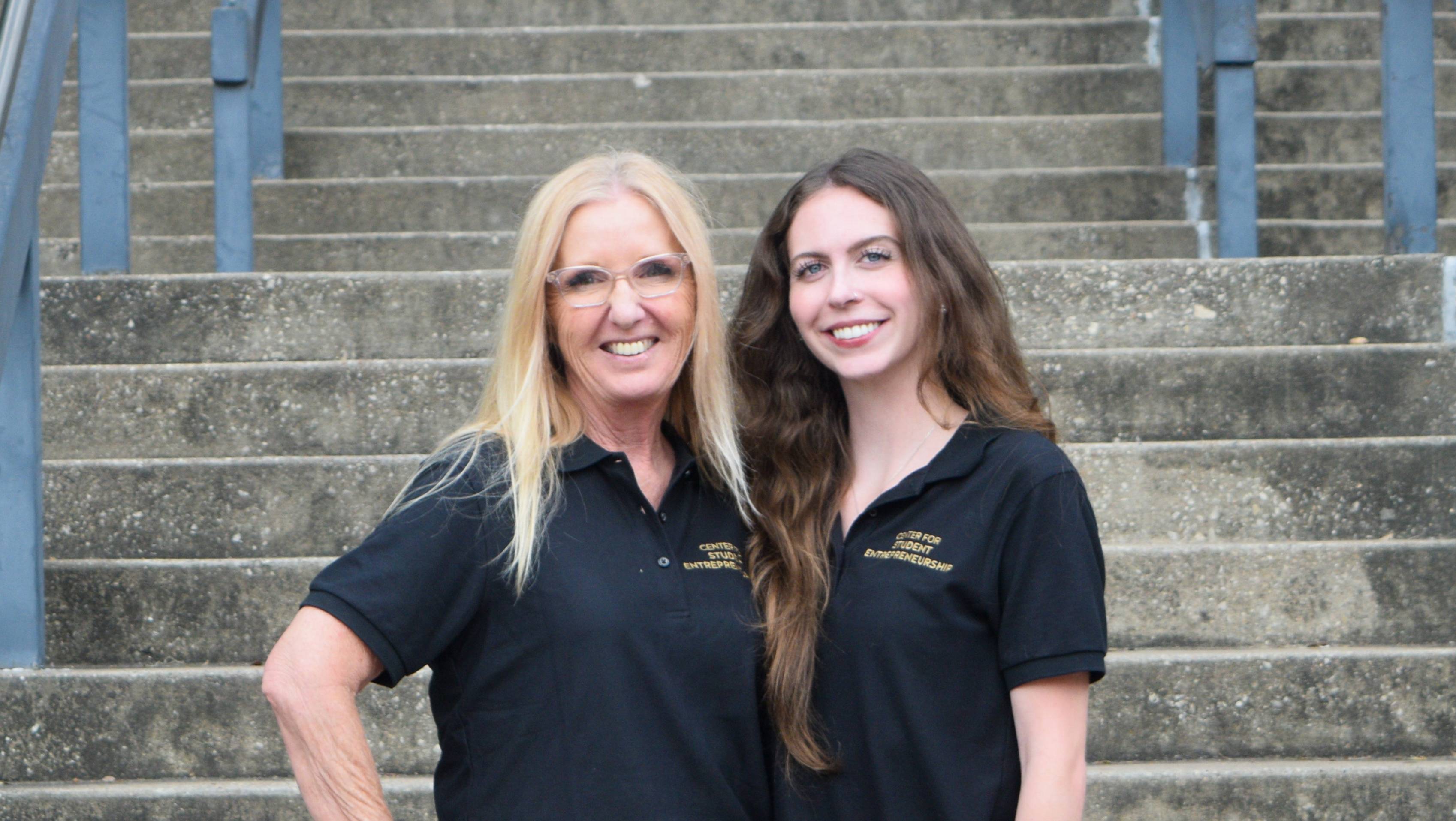 two women posing for photo in black polo shirts