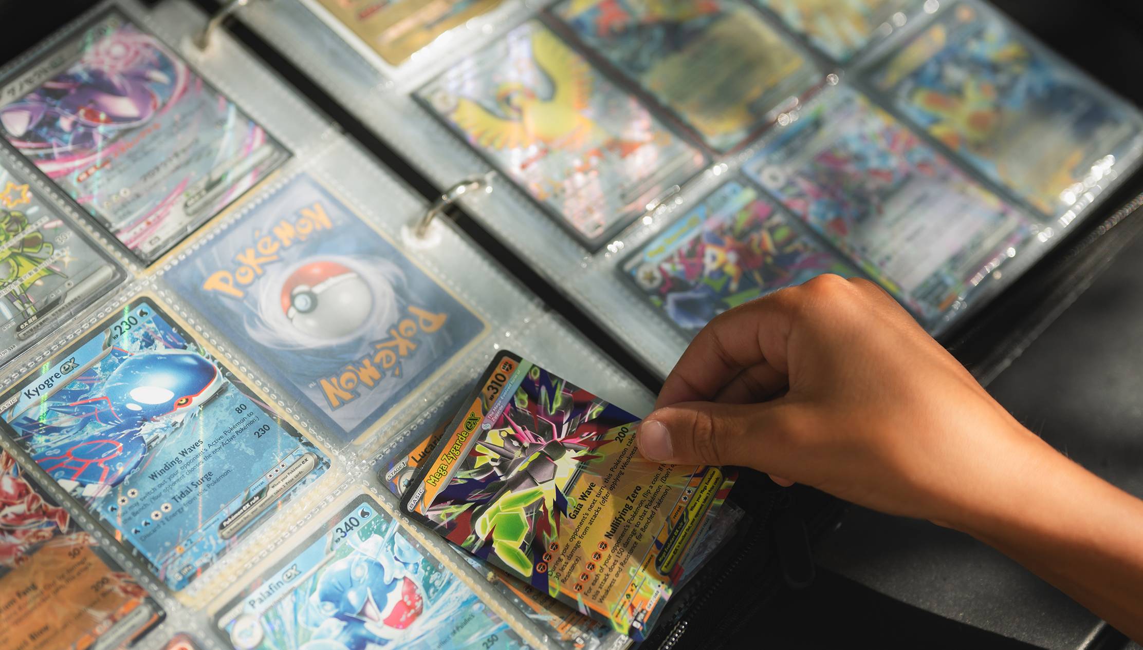 hand pulling out pokemon card from a binder with protective sheets