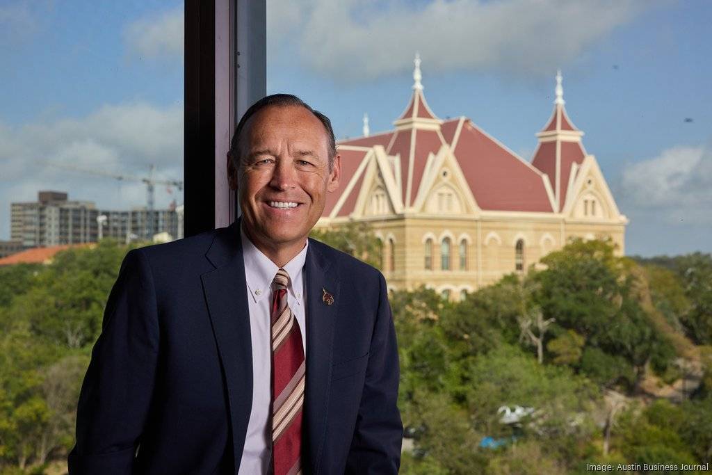 president damphousse smiling in front of window with txst's old main in background
