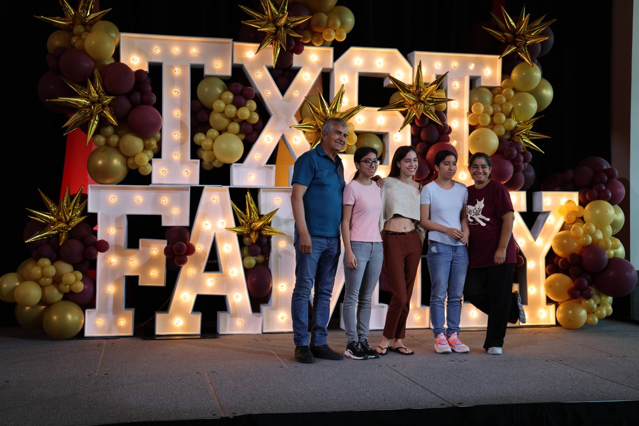 Family posing in front of family weekend sign
