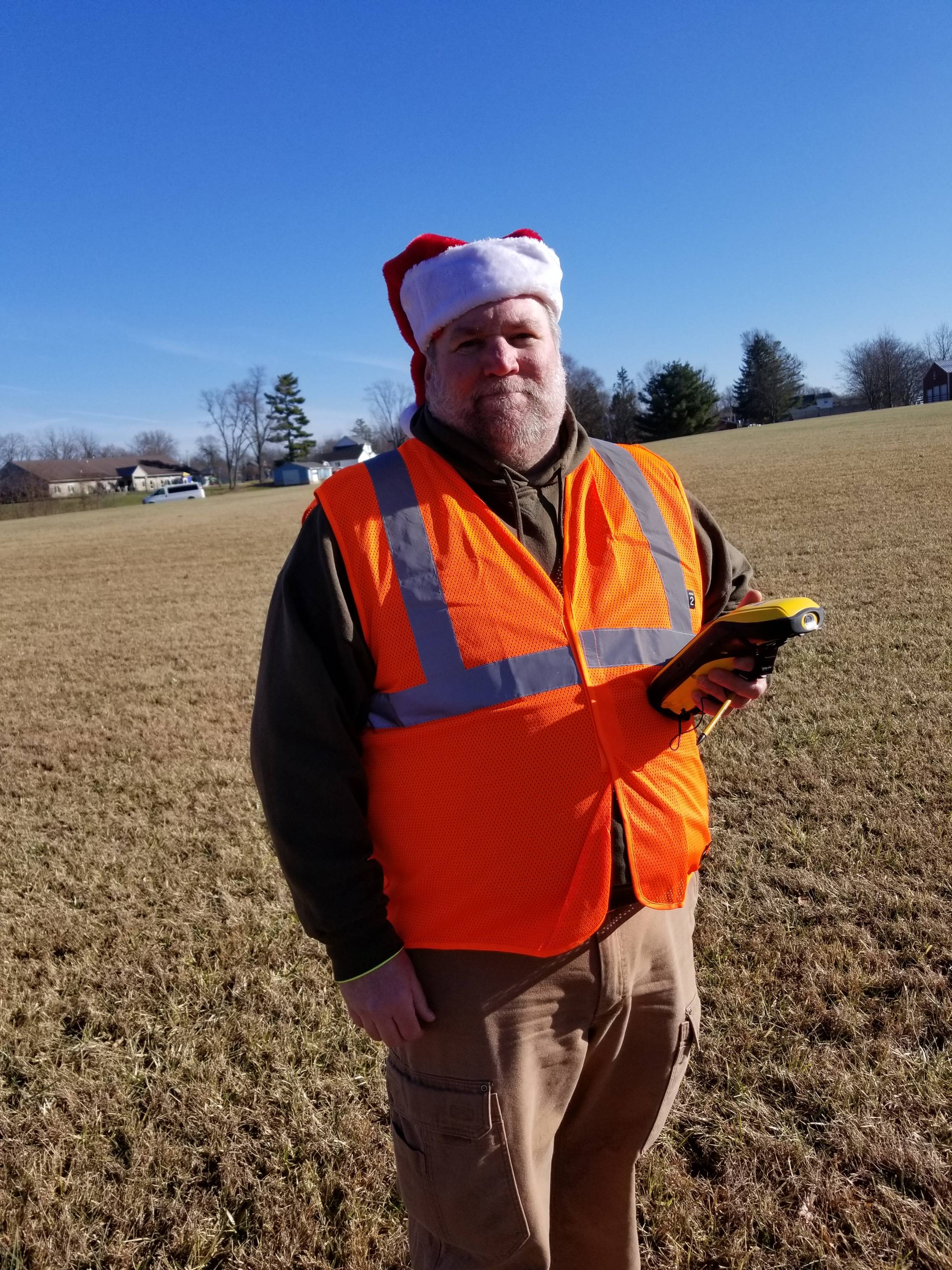 Sean in the field with a GPS and santa hat