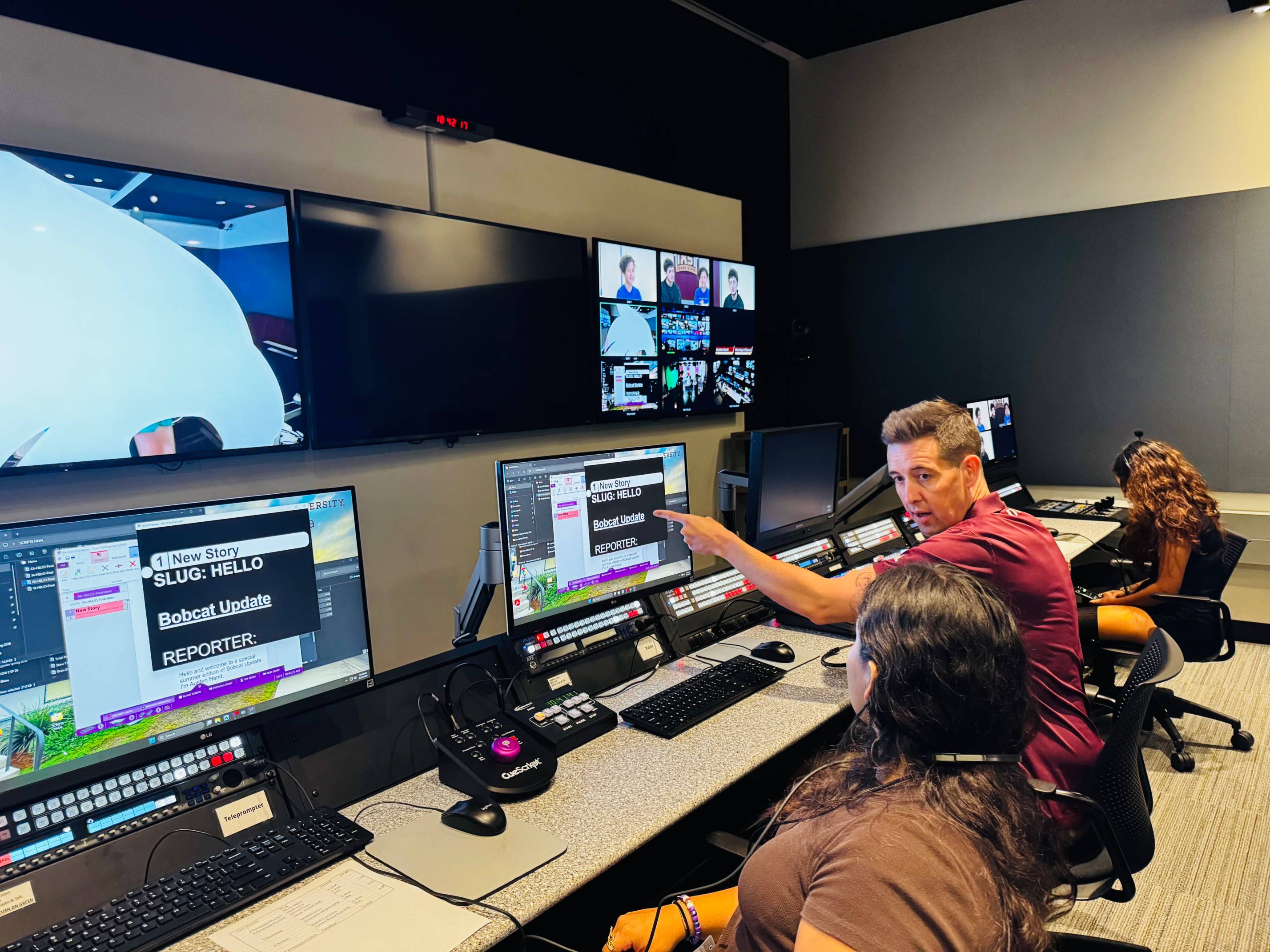 Professor Dan Seed is pointing to the monitor to a student, teaching them