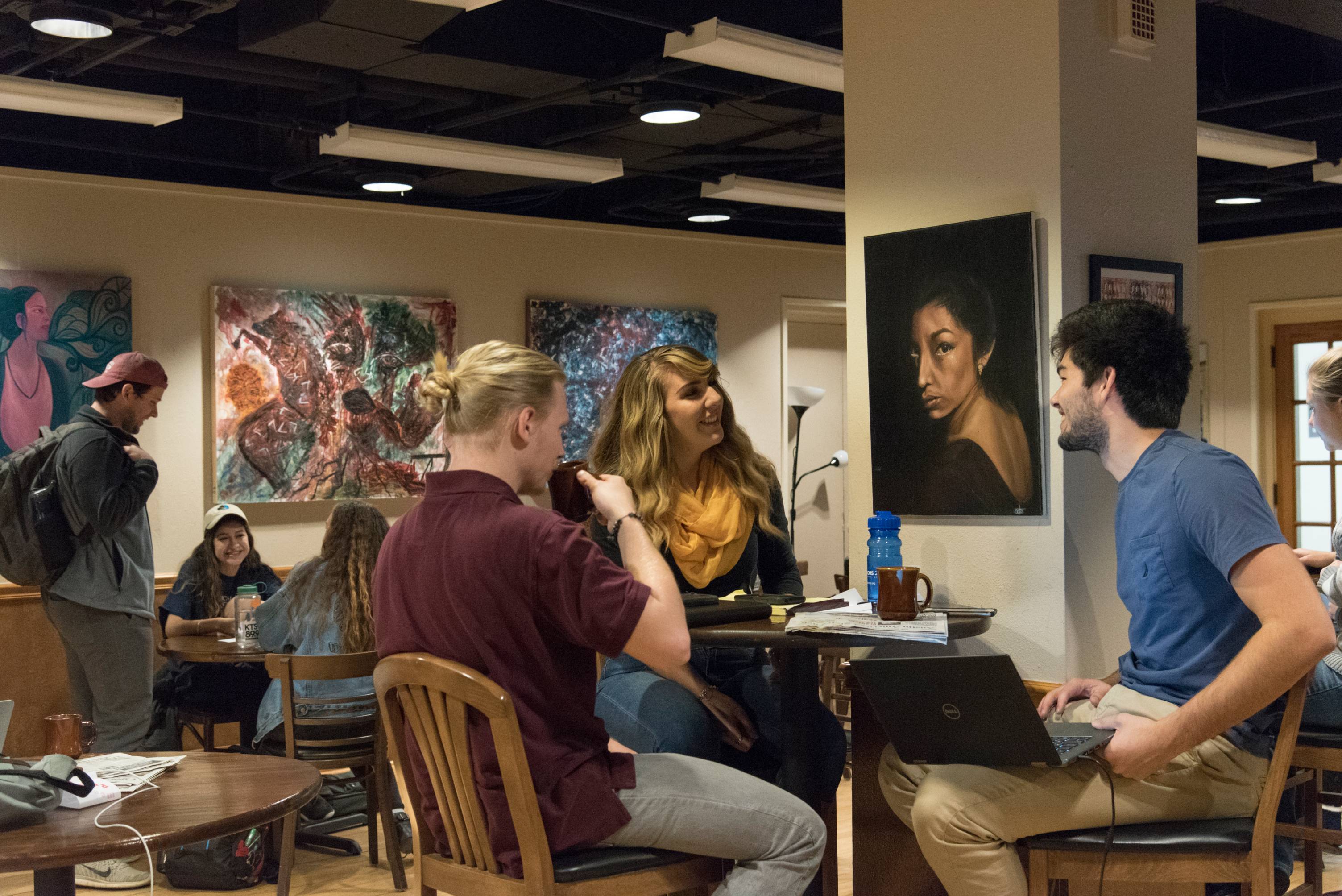 A group of students chatting at a table in the honors college cafe.
