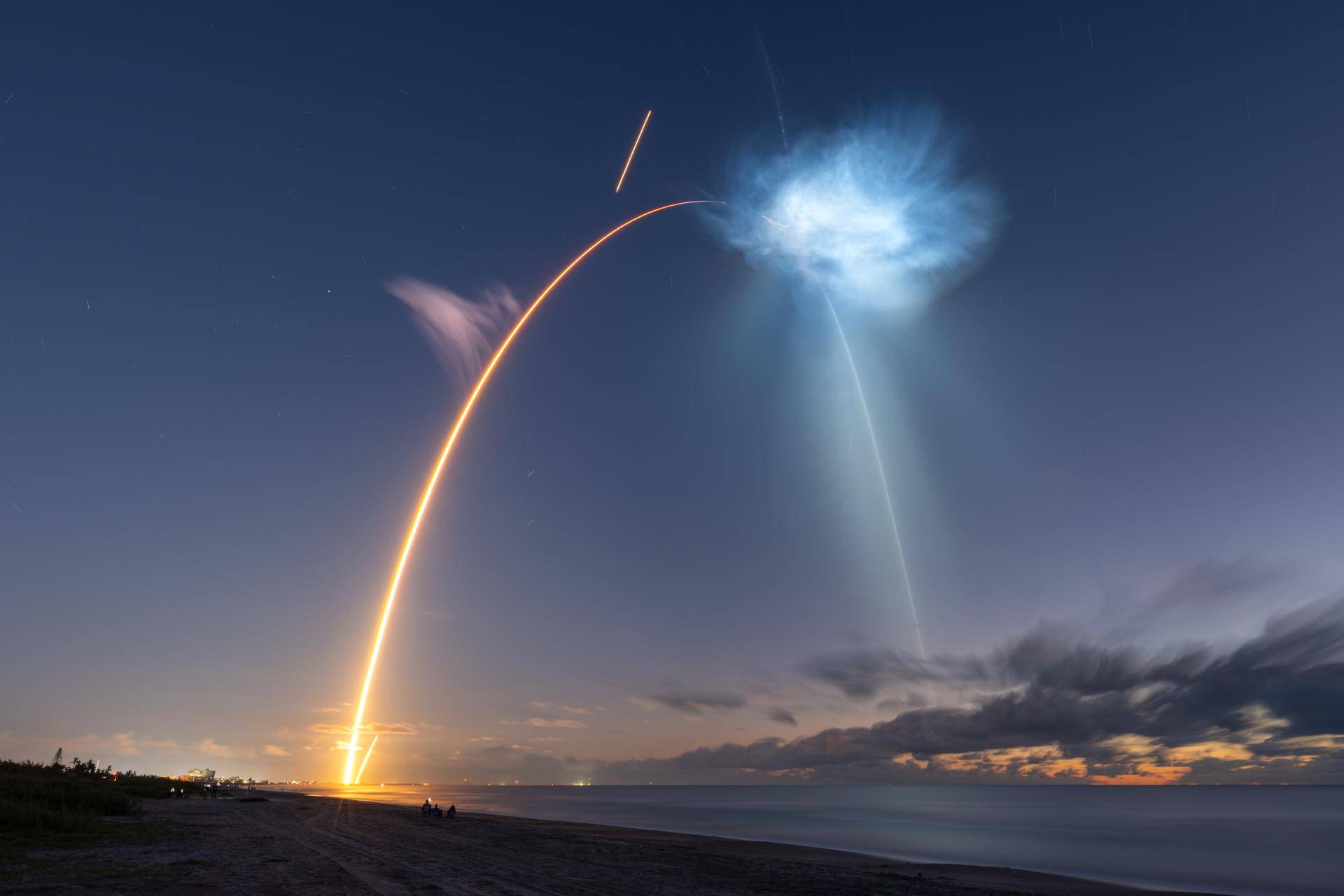 timelapse shows the yellow curve of a rocket launching into space during early morning