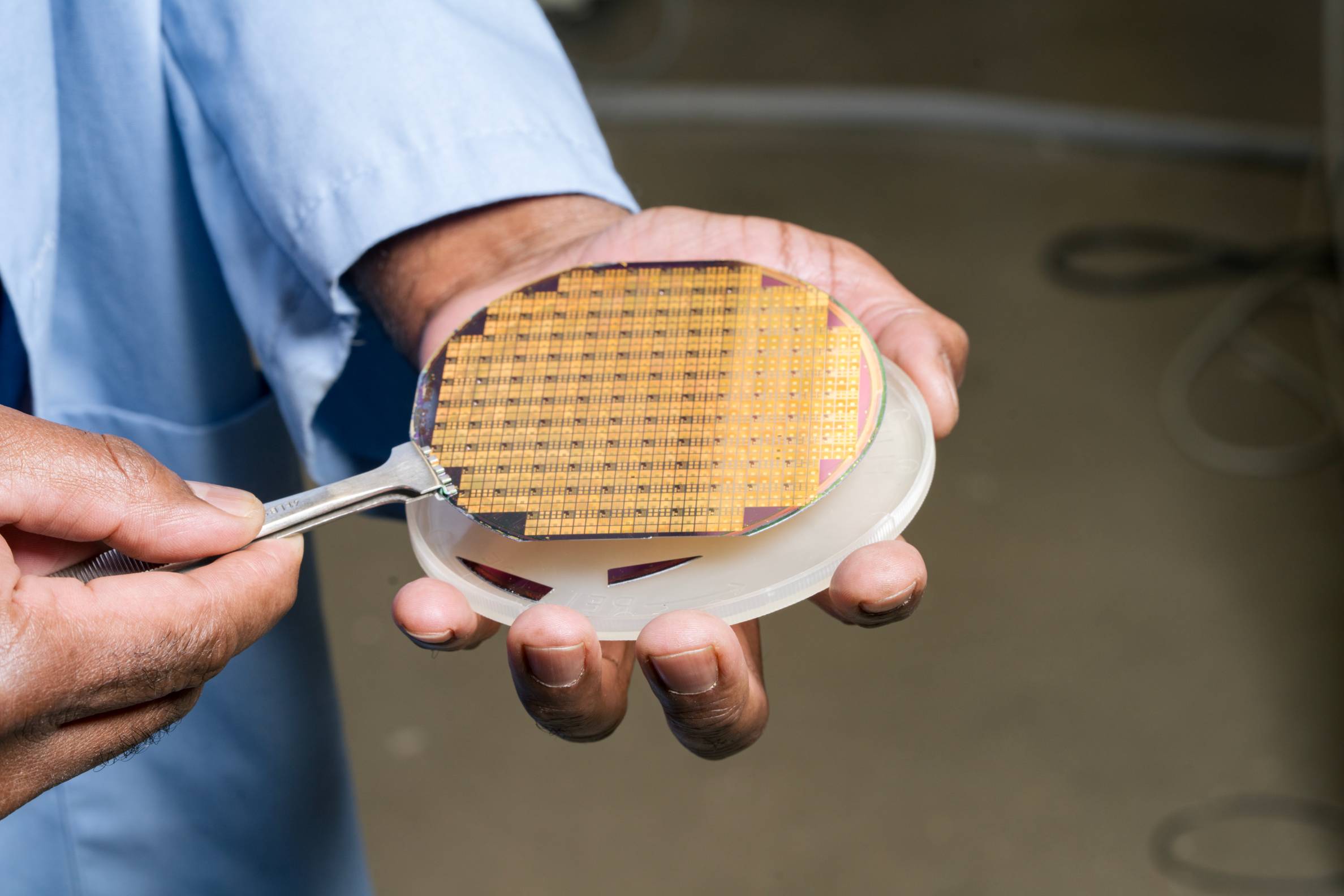 gold semiconductor wafer held in someone's hand