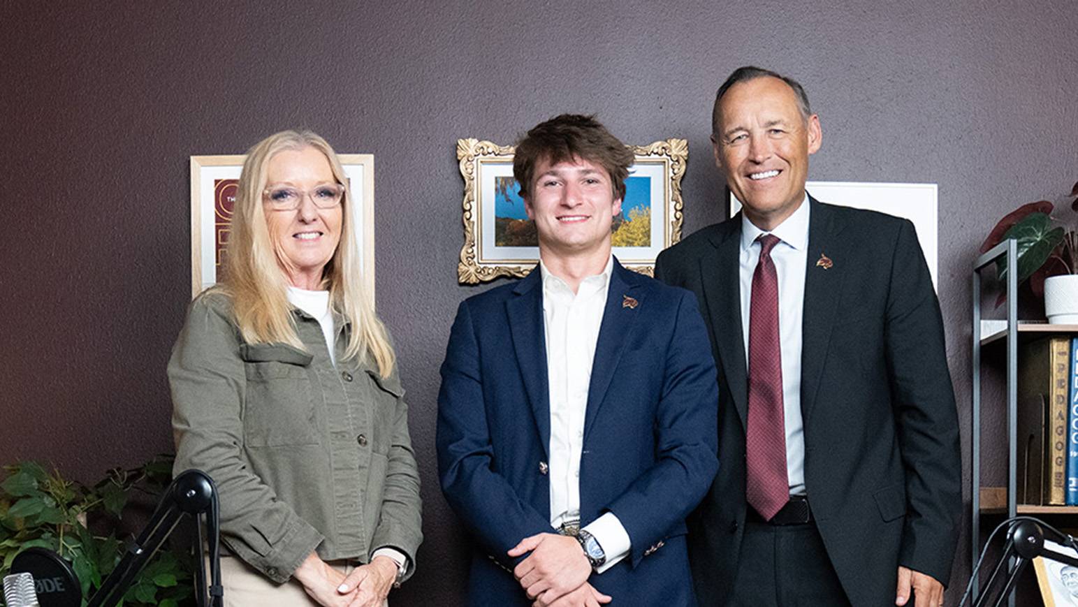 woman and two men pose for photo in dark maroon room