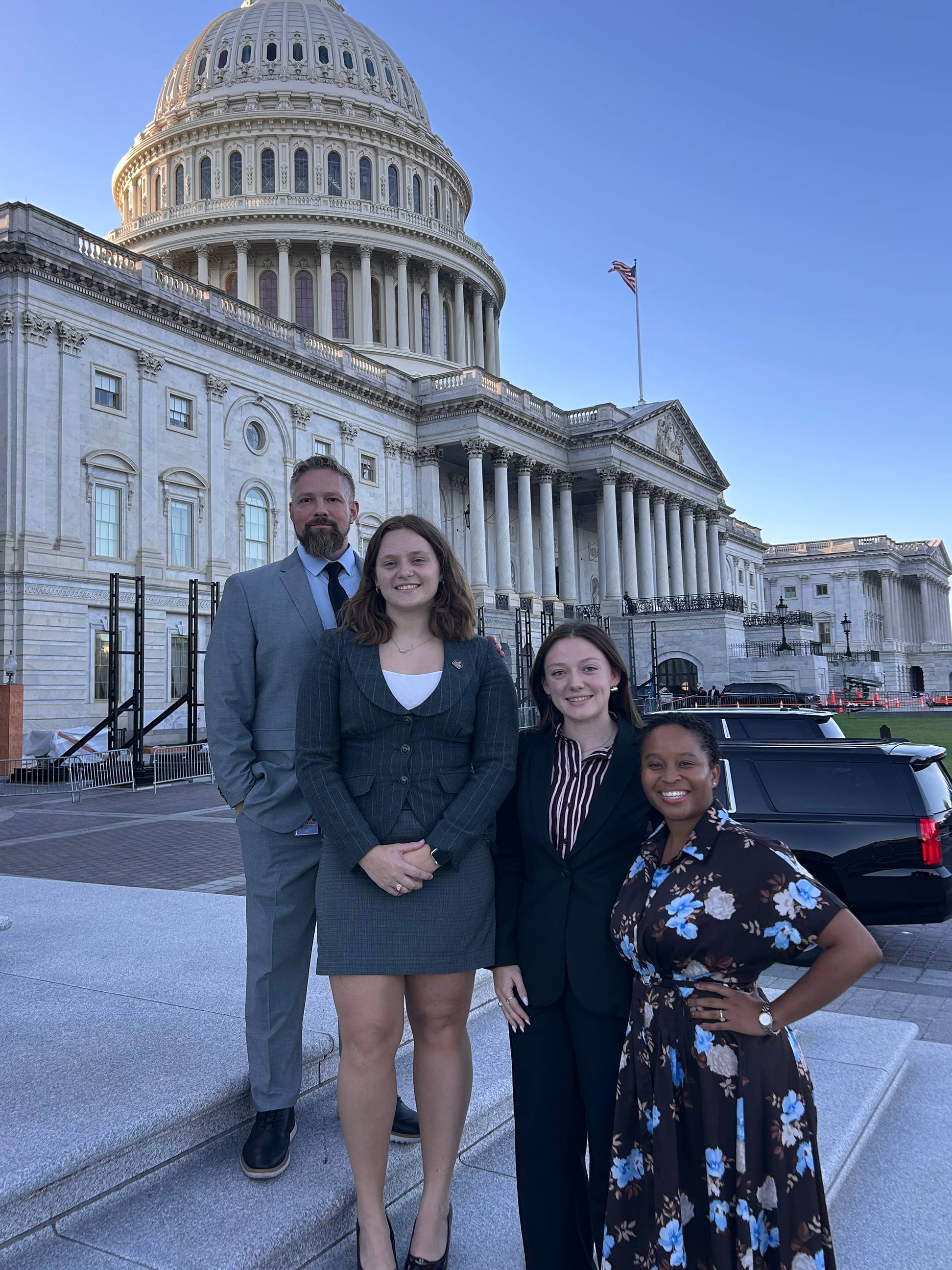 four people standing on steps outside U.S. Capitol building