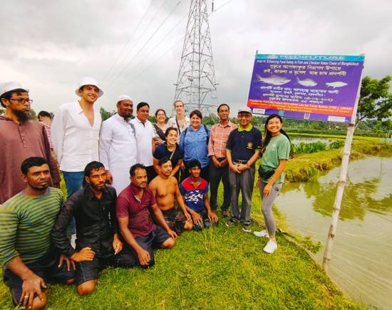 large group of people standing next to pond in Bangladesh