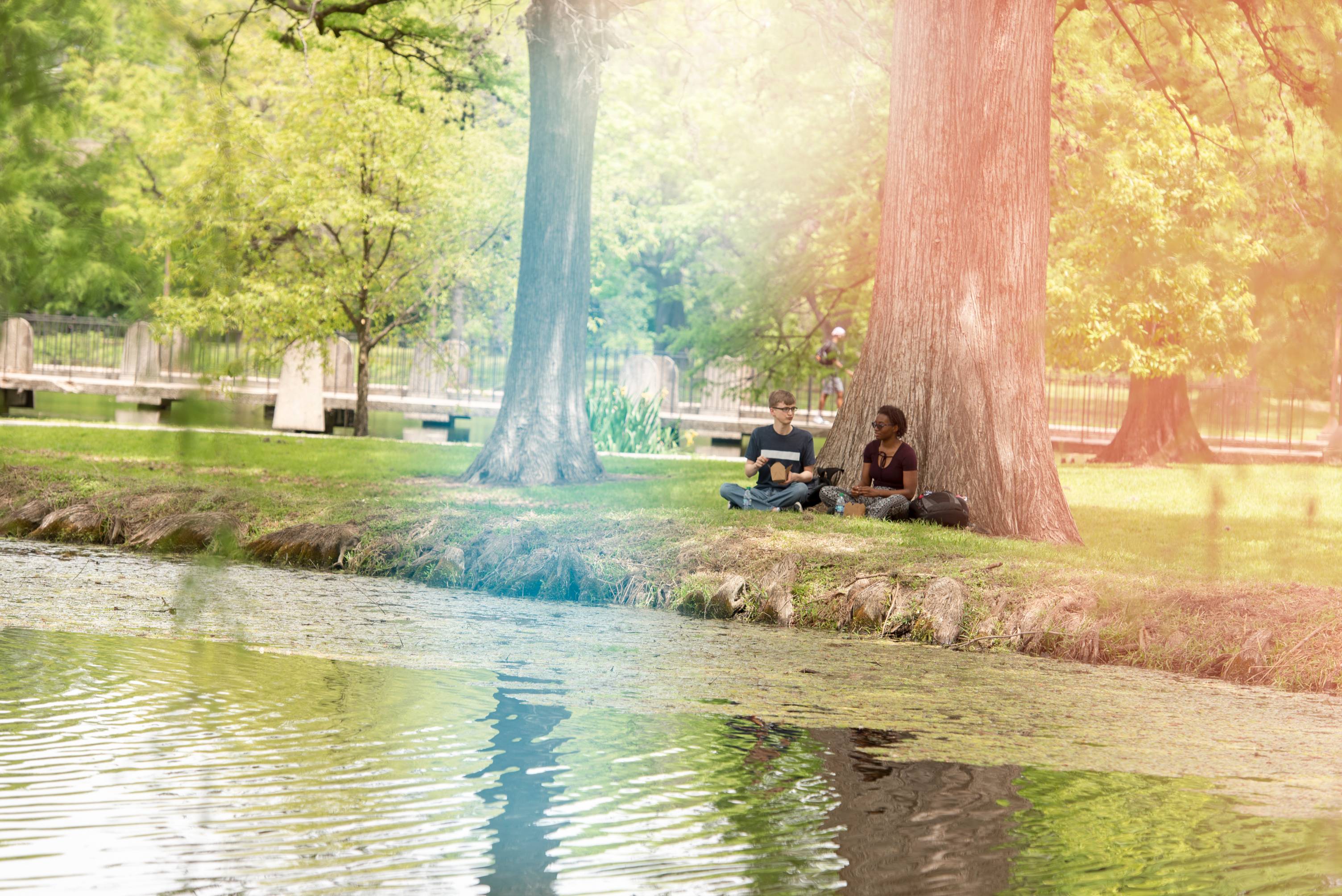 Photo of two student by the ponds near JCK/Theatre Building