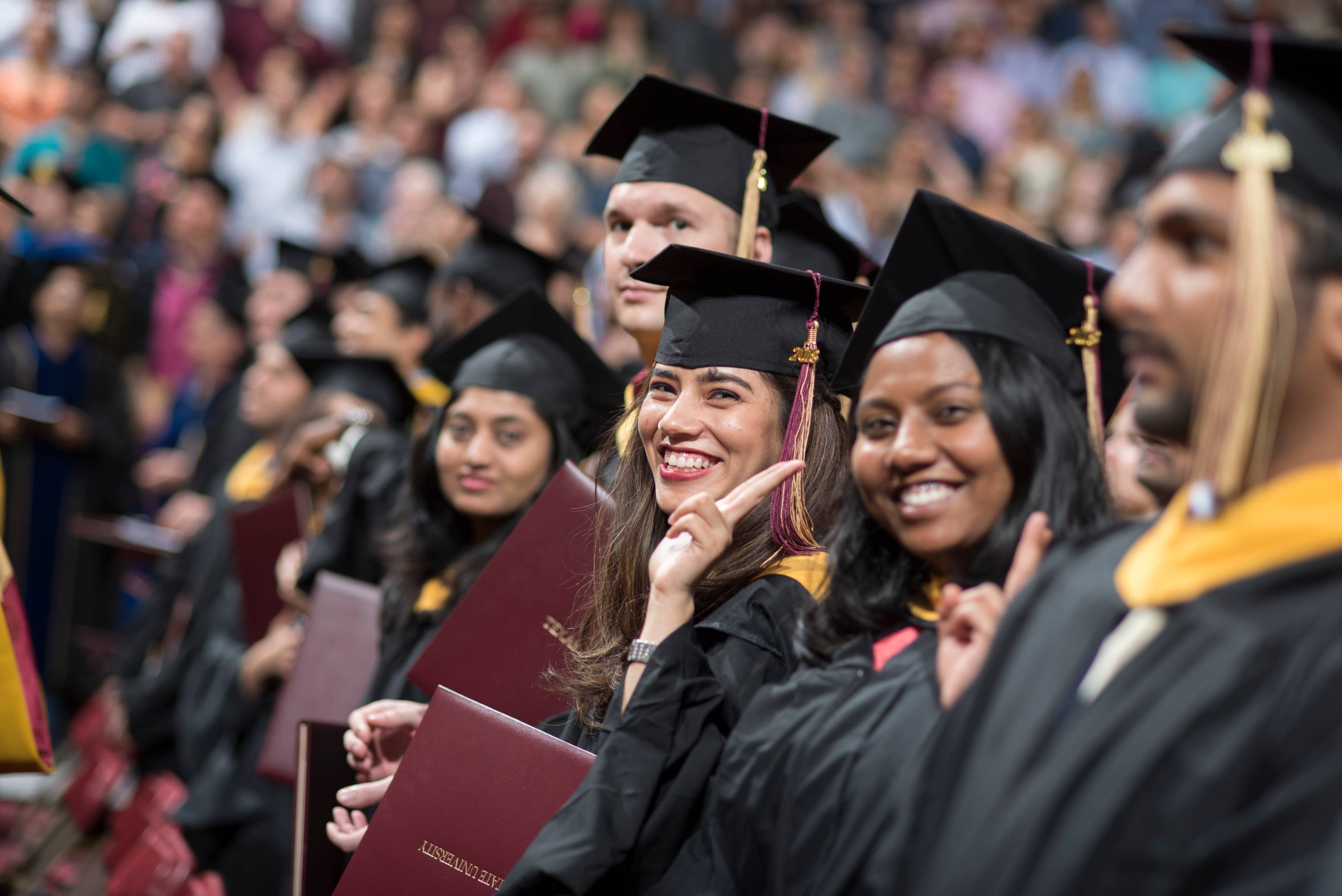 students at txst graduation waving their hands in celebration